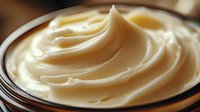 Creamy vanilla pudding with smooth swirled texture in glass bowl, macro shot showing rich dessert consistency and glossy surface in warm lighting.