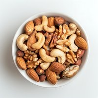 Mixed raw nuts in white ceramic bowl on light background, including almonds, cashews, walnuts, pecans and hazelnuts, top view food photography.