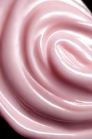 Soft pink swirling abstract background with gentle curves and light effects creating an elegant rose-like pattern against dark backdrop. Suitable for luxury product designs.