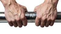 Strong masculine hands gripping chrome barbell bar showing determination and strength training commitment for fitness workout routines.