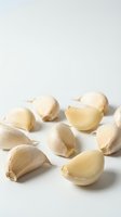 Isolated garlic cloves and whole bulbs arranged on white background, some peeled and halved showing fresh interior, perfect for culinary and food styling projects.