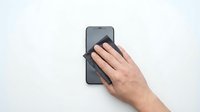 Close-up of a hand holding a smartphone on white background, isolated for design use on marketing materials, websites, and digital applications.