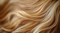 Flowing golden blonde wavy hair texture with highlights and lowlights creating dynamic movement and shine, closeup macro view for hair and beauty industry.