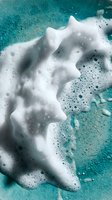 White foam bubbles floating on turquoise water surface creating abstract patterns for spa wellness and cleaning product advertisements.