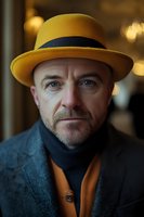 Middle-aged Caucasian man with beard wearing yellow fedora hat and gray coat in warm indoor setting with bokeh lights for lifestyle photography.