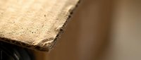 Aged weathered wood plank corner with rough textured surface and natural grain patterns showing wear and patina for rustic carpentry projects.