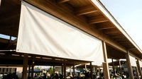 Blank white horizontal banner hanging on wooden structure at outdoor market, mockup with copy space for text or logo design.