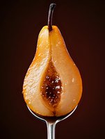 Sliced pear with seeds displayed on glass stem against dark background, isolated for food photography, culinary design, and healthy eating concepts.