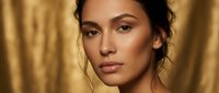 Young mixed-race woman with glowing skin and natural makeup in warm golden lighting for beauty and skincare campaigns.