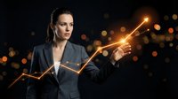 Professional businesswoman in dark suit touching glowing upward trending arrow chart against bokeh background representing growth and success.