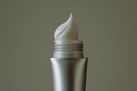 Silver cosmetic tube with white cream swirl on top, close-up shot on neutral background, skincare product concept.