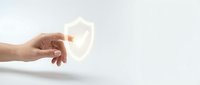 Hand holding glowing shield icon representing cybersecurity protection and data safety on clean white background for business presentations.