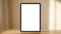Digital tablet with blank white screen standing on wooden table in warm sunlit room for mockup presentations and app development projects.