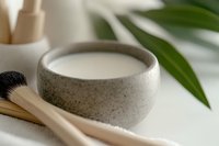 Minimalist ceramic bowl with matcha tea and bamboo whisk on white surface, green leaf accent creates zen atmosphere for wellness and meditation practices.