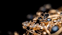 Delicate gold jewelry with dark blue sapphires and diamonds on black background, macro shot showing intricate floral design details and precious stones in luxury setting.