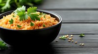 Cooked bulgur wheat with fresh herbs in black bowl on wooden table. Healthy whole grain pilaf garnished with parsley leaves for nutritious meal preparation.