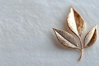 Elegant rose gold leaf brooch with delicate veined texture on light textured background, minimalist jewelry design for fashion and accessories.