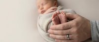 Parent holding newborn baby feet in hands, close-up shot capturing tender bonding moment. Maternity, parenthood, family care, and new life concept for healthcare and family-related projects.