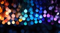 Glowing colorful Christmas balls arranged in rainbow gradient pattern against dark background create magical festive atmosphere with bokeh light effect.