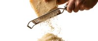 Hand grating hard parmesan cheese with a metal grater, shavings falling on white background, captured in motion for food and cooking content.