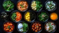 Korean side dishes banchan variety in black bowls from above featuring kimchi, pickled vegetables, marinated tofu, seaweed, and traditional fermented accompaniments.