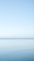 Serene seascape with calm ocean waters meeting clear sky at horizon, minimalist coastal landscape for travel, wellness, and meditation design projects.