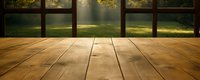 Empty wooden table surface with blurred green garden background through panoramic window, sunbeams streaming through trees create atmospheric morning scene.