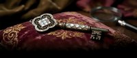 Ornate vintage key with decorative handle resting on antique burgundy book with golden embossed cover design creating mysterious atmospheric composition.
