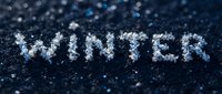 Word WINTER spelled with real snowflakes on dark blue frozen surface, macro close-up with bokeh background for seasonal design.