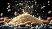 Ground almond flour with whole nuts scattered around on dark background with flour particles floating in air creating magical baking atmosphere.
