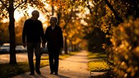 Senior couple walking together on autumn path during golden hour sunset creating romantic silhouette against warm bokeh light through trees.