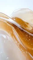 Golden honey flowing in smooth waves with bubbles and translucent texture for natural skincare cosmetics packaging design.