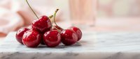 Fresh ripe red cherries with stems on white wooden surface, healthy organic summer fruit for cooking, baking and desserts.
