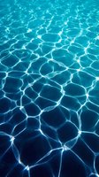 Crystal clear turquoise swimming pool water with sunlight creating rippling patterns and reflections on the surface for summer vacation backgrounds.