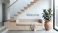 Modern minimalist entryway with wooden staircase, built-in bench, cozy throw, and lush plant, featuring a welcome sign on white wall.