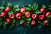 Fresh red apples with green leaves arranged on dark teal background, perfect for food photography, restaurant menu design, or healthy eating concept. Moody lighting creates dramatic atmosphere.