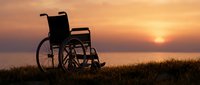 Empty wheelchair silhouette against golden sunset over water and grass field, symbolizing hope, recovery, accessibility, and overcoming physical challenges.
