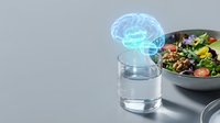 Glowing brain hologram above water glass next to healthy salad bowl representing mind-body nutrition connection and cognitive wellness through diet.