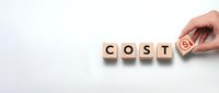 Hand placing wooden cube with dollar sign to complete the word COST on white background, symbolizing financial planning and budget management.