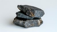 Stack of raw dark gray shale rock fragments showing natural layered texture and rough surfaces against white background, isolated for geology and mineral studies.
