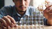 Young businessman building wooden blocks with percentage symbols showing growth strategy and financial planning for investment success.