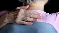 Caring hand on shoulder showing support and comfort during difficult times, emotional connection between people in pink and blue casual clothing.