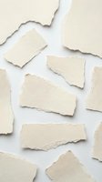 Torn cream paper pieces scattered on white background with rough edges and natural texture for creative design projects and artistic layouts.