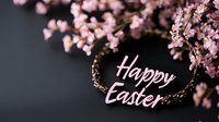 Pink cherry blossoms frame elegant Happy Easter text on dark background, creating seasonal spring holiday greeting card composition with delicate floral elements.