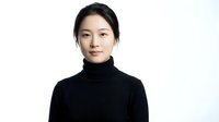 Professional Asian woman in black turtleneck sweater against white background, confident business portrait for corporate marketing materials.