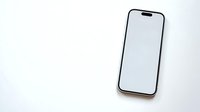 Modern smartphone with blank white screen lying on clean white surface for mockup and app presentation designs.