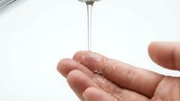 Clean water flowing from modern faucet into cupped hands showing hygiene and freshness in bathroom or kitchen setting for health and wellness concepts.