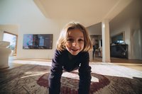 Smiling young girl in dark sweater playing on carpet in spacious living room with natural light streaming through windows.
