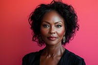 Confident African American businesswoman with natural curly hair and professional attire smiling against pink background, expressing leadership and success.