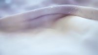 Soft flowing fabric with delicate purple and cream tones creating elegant waves and gentle curves for luxury textile and fashion design backgrounds.